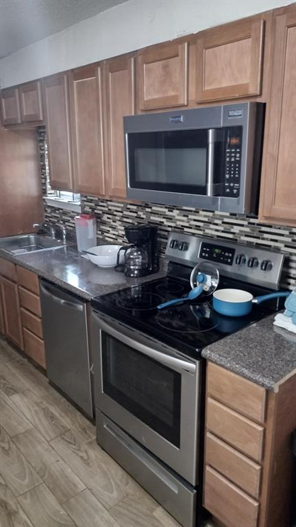 304 Ridgewood Drive Tool, TX 75143 - Photo 5 of 12 Kitchen featuring stainless steel appliances, light wood-style floors, wood finish cabinets, dark stone countertops, and decorative backsplash