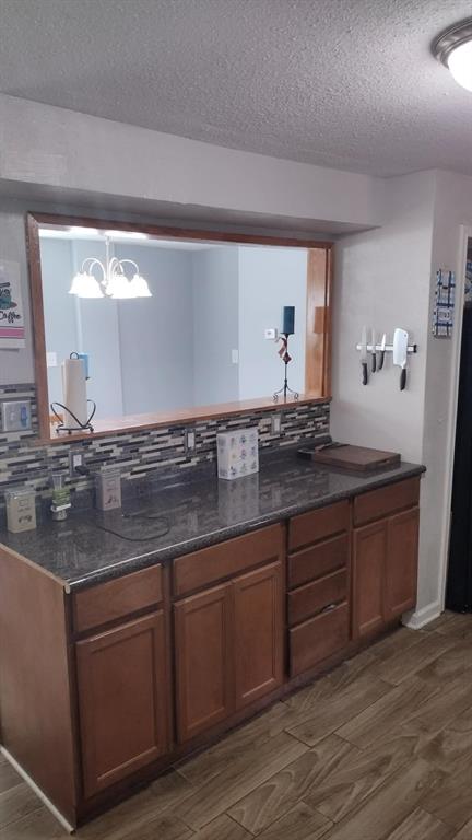 304 Ridgewood Drive Tool, TX 75143 - Photo 9 of 12 Kitchen with tasteful backsplash, wood finish floors, wood finish cabinets, a textured ceiling, and dark stone counters