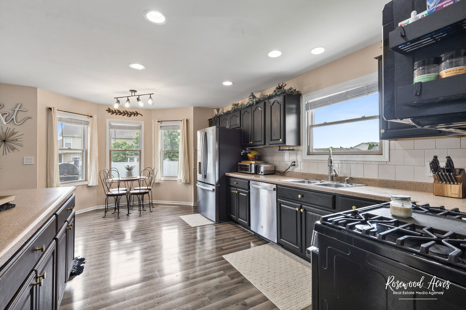 840 Peony Lane Bourbonnais, IL 60914 - Photo 9 of 30 a kitchen with stainless steel appliances granite countertop a stove top oven a sink dishwasher a dining table and chairs with wooden floor