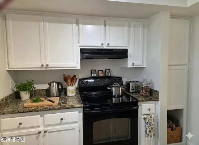 a kitchen with granite countertop white cabinets and black appliances