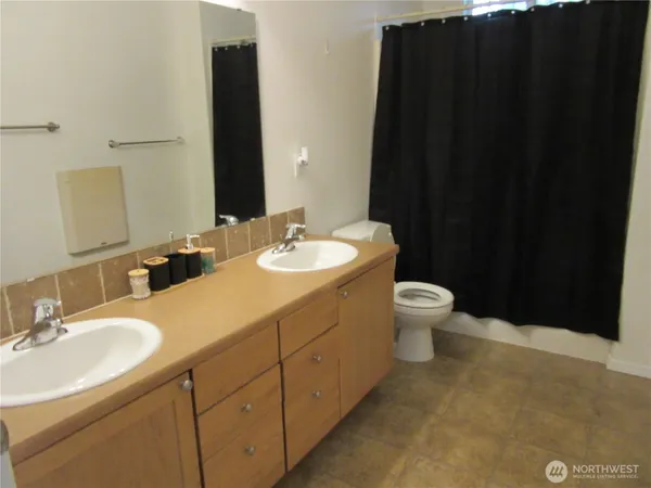 a bathroom with a double vanity sink toilet and a mirror