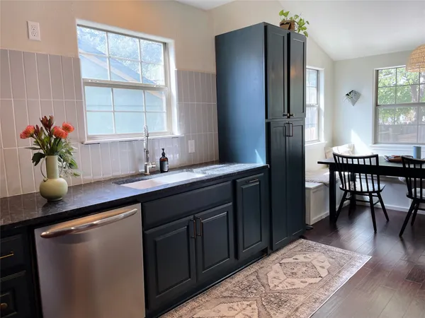 a kitchen with stainless steel appliances granite countertop a sink dishwasher a dining table and chairs with wooden floor