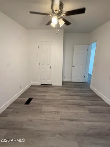 a view of a room with wooden floor and a ceiling fan