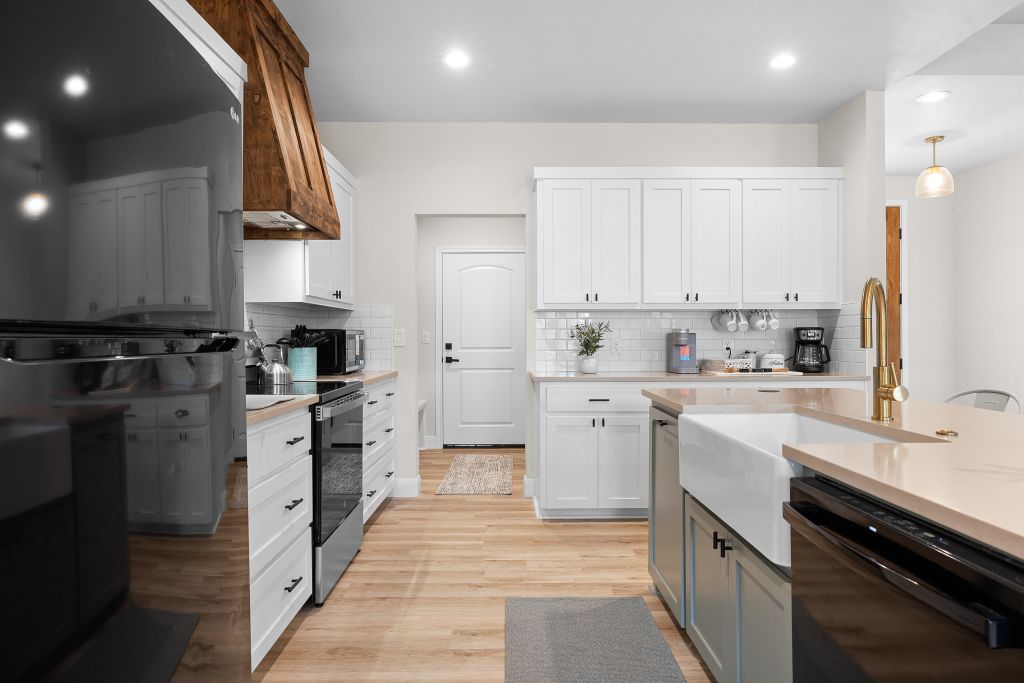 An inviting kitchen displays sleek countertops alongside light wood flooring and classic cabinetry.