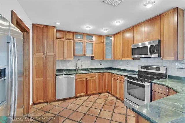 a kitchen with stainless steel appliances granite countertop a refrigerator and a stove top oven