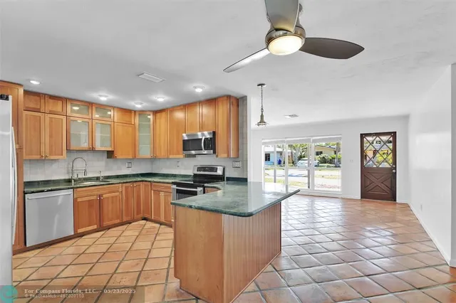 a open kitchen with stainless steel appliances granite countertop a stove top oven a sink dishwasher a dining table and chairs with wooden floor