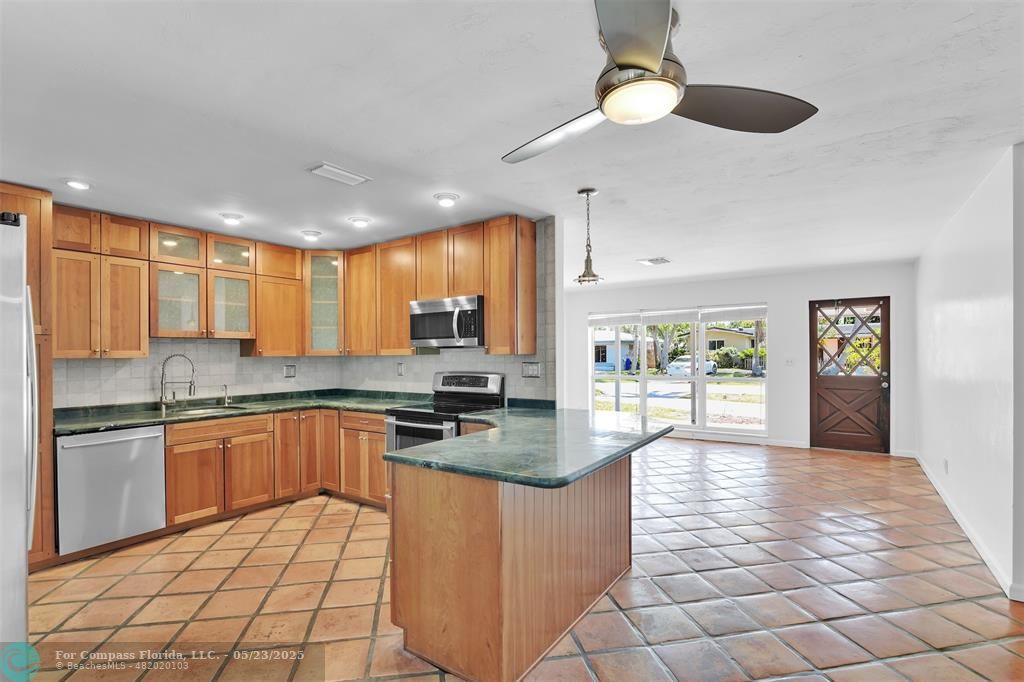 341 Southeast 8th Street Pompano Beach, FL 33060 - Photo 7 of 56 a open kitchen with stainless steel appliances granite countertop a stove top oven a sink dishwasher a dining table and chairs with wooden floor