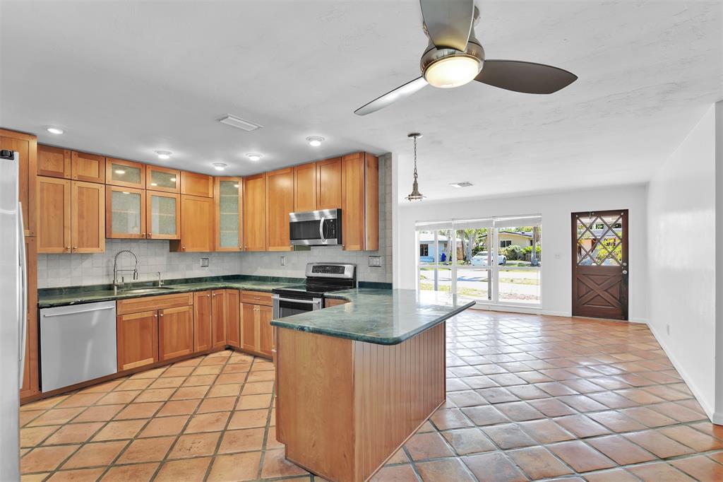 341 Southeast 8th Street Pompano Beach, FL 33060 - Photo 7 of 56 a kitchen with stainless steel appliances granite countertop a stove top oven a sink dishwasher a dining table and chairs with wooden floor