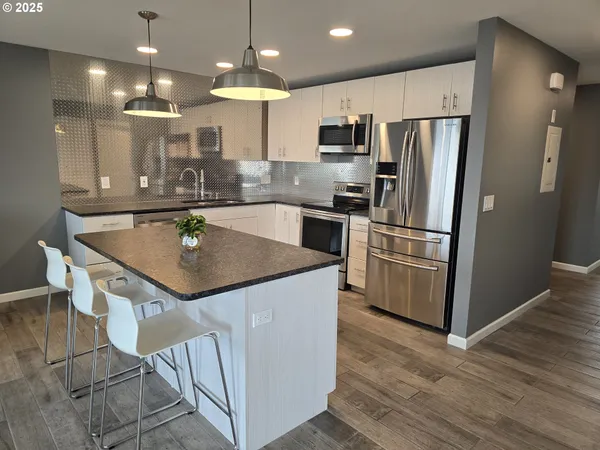 a kitchen with kitchen island a counter top space a sink appliances and cabinets