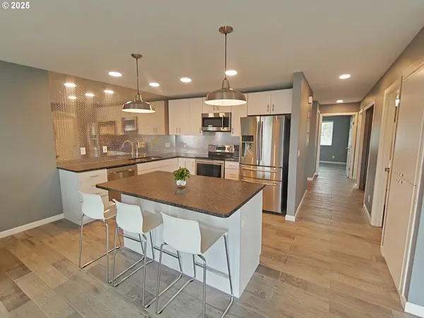 a kitchen with stainless steel appliances kitchen island granite countertop a refrigerator and a sink