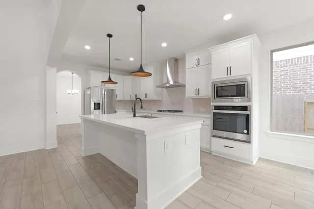 a large kitchen with stainless steel appliances kitchen island granite countertop a sink a microwave and a refrigerator