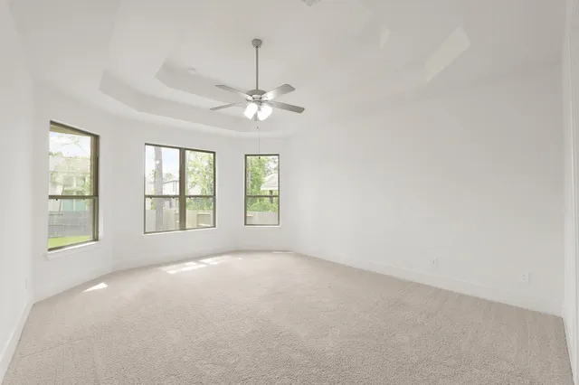an empty room with chandelier fan and windows