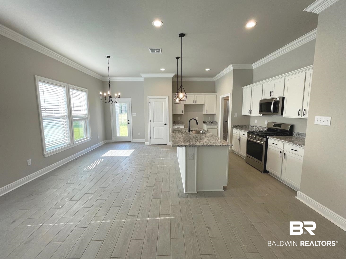 1634 Fenton Circle Foley, AL 36535 - Photo 2 of 14 Kitchen featuring stainless steel appliances, an island with sink, sink, ornamental molding, and white cabinetry