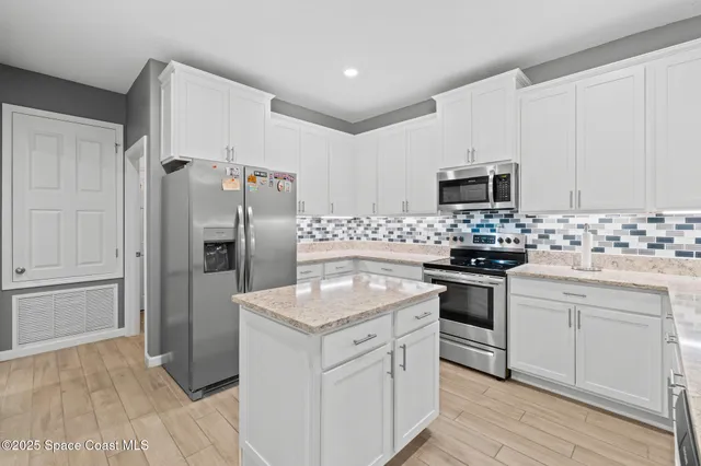 a kitchen with a sink granite counter tops and a view of living room