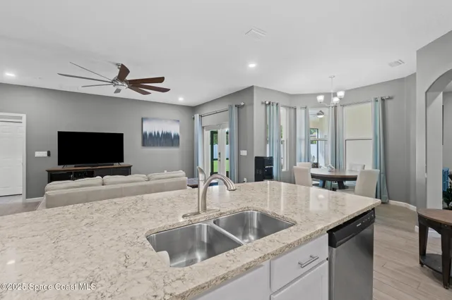 a large white kitchen with stainless steel appliances kitchen island granite countertop a dining table chairs and granite counter tops