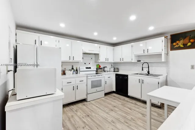 a kitchen with white cabinets white appliances and sink