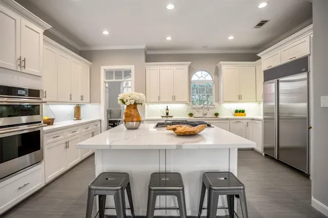 a kitchen with stainless steel appliances a sink a stove a refrigerator cabinets and dining table