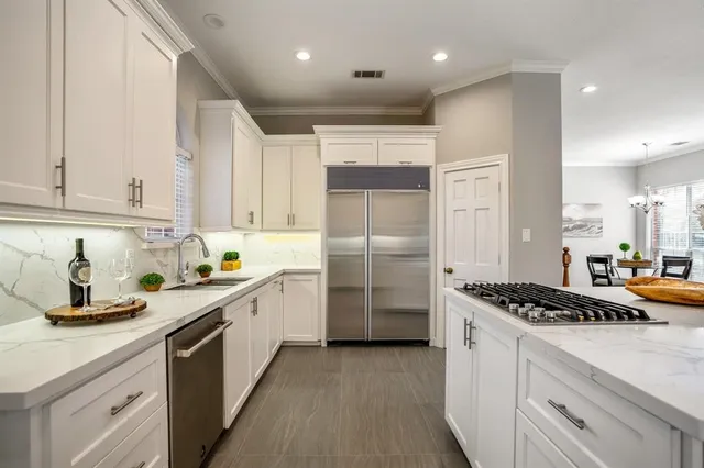 a kitchen with stainless steel appliances a sink a stove a refrigerator and cabinets