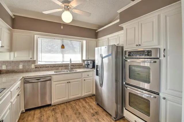 a kitchen with white cabinets and stainless steel appliances