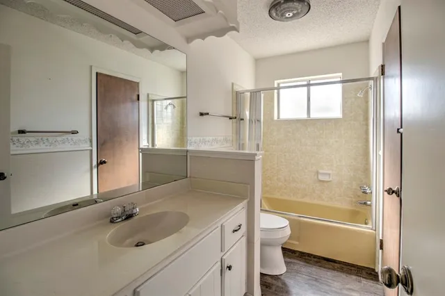 a bathroom with a granite countertop sink a toilet and shower