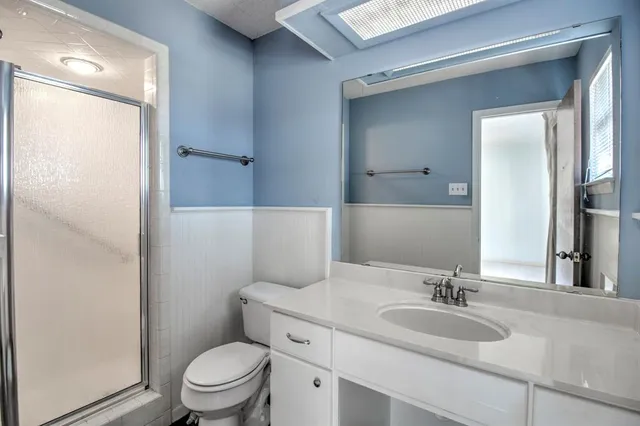 a bathroom with a granite countertop sink toilet a mirror and shower