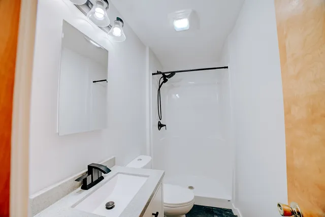 a bathroom with a sink a toilet and shower