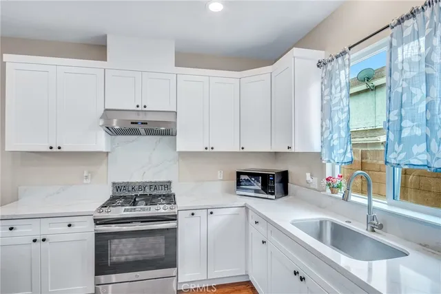 a kitchen with white cabinets white stainless steel appliances and sink