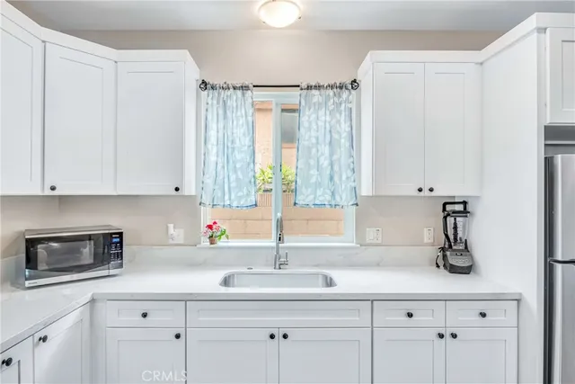 a kitchen with white cabinets and sink