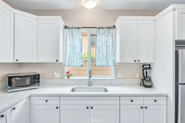 a kitchen with white cabinets and sink