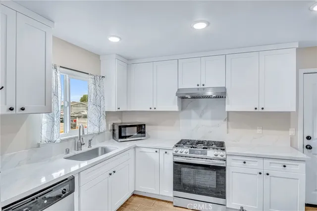 a kitchen with granite countertop white cabinets and white stainless steel appliances