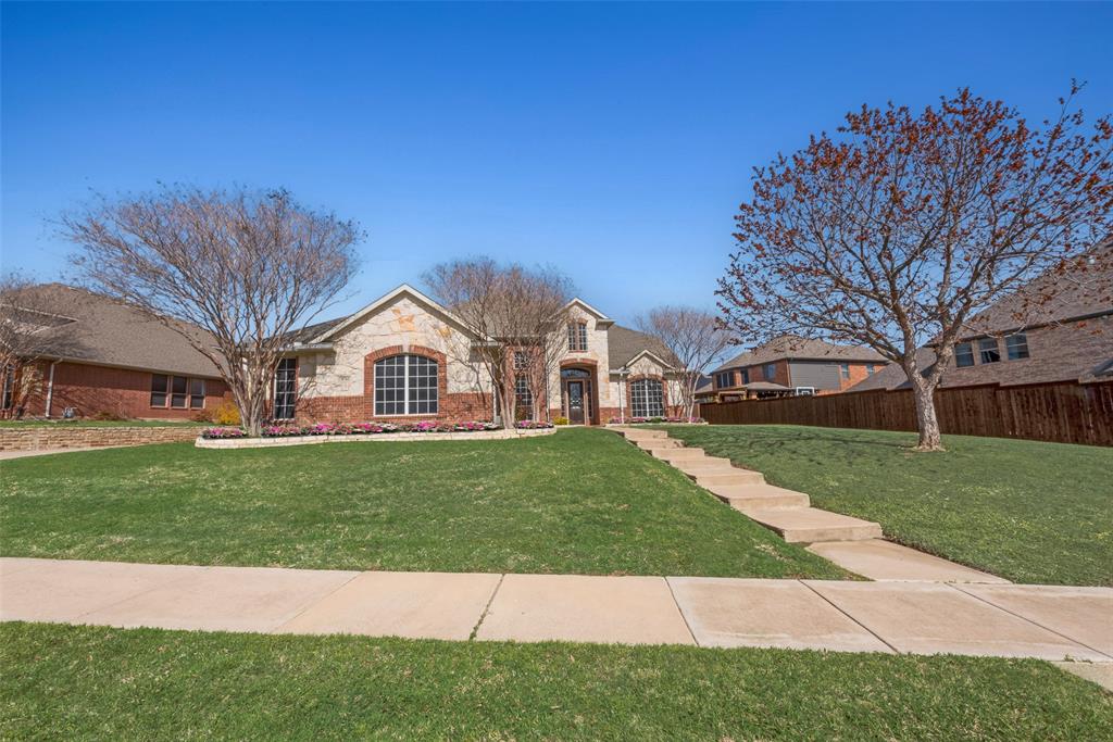 View of front of property with brick siding, a front yard, fence, and stone siding