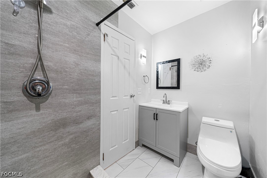 2335 50th Terrace Southwest Naples, FL 34116 - Photo 11 of 26 a bathroom with a toilet a sink and mirror