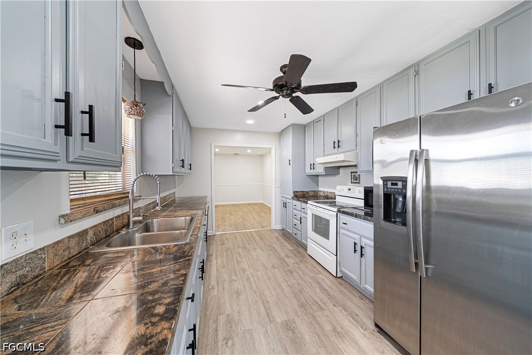 2335 50th Terrace Southwest Naples, FL 34116 - Photo 6 of 26 a kitchen with granite countertop a refrigerator a sink a stove and white cabinets