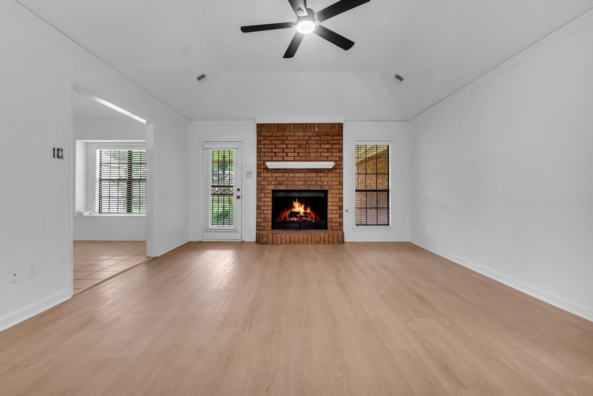 6613 Stephan Ridge Drive Bartlett, TN 38135 - Photo 5 of 24 Spacious room featuring light wood-finish flooring, a brick fireplace with a white mantel, and a black ceiling fan