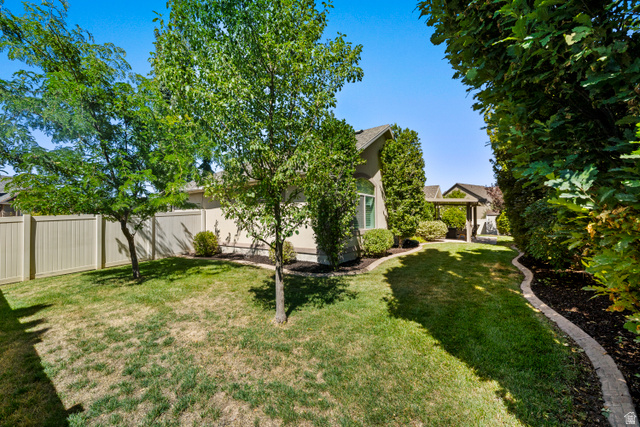 564 Spring Meadow Lane Farmington, UT 84025 - Photo 28 of 31 Expansive backyard featuring a manicured lawn, established trees, and perimeter fencing