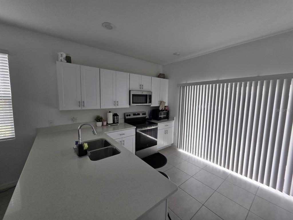 3318 Composition Street Kissimmee, FL 34758 - Photo 11 of 28 a kitchen with stainless steel appliances a sink a stove a microwave and cabinets