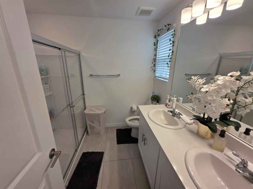 3318 Composition Street Kissimmee, FL 34758 - Photo 16 of 28 a bathroom with a sink a toilet a mirror and shower