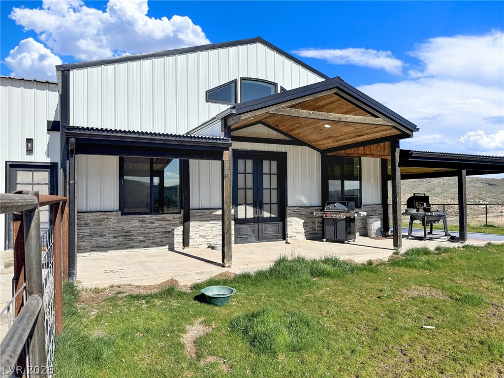 9393 North 93rd Highway Caliente, NV 89008 - Photo 2 of 41 A modern facade with corrugated siding offers a welcoming covered patio and a separate covered outdoor cooking area.
