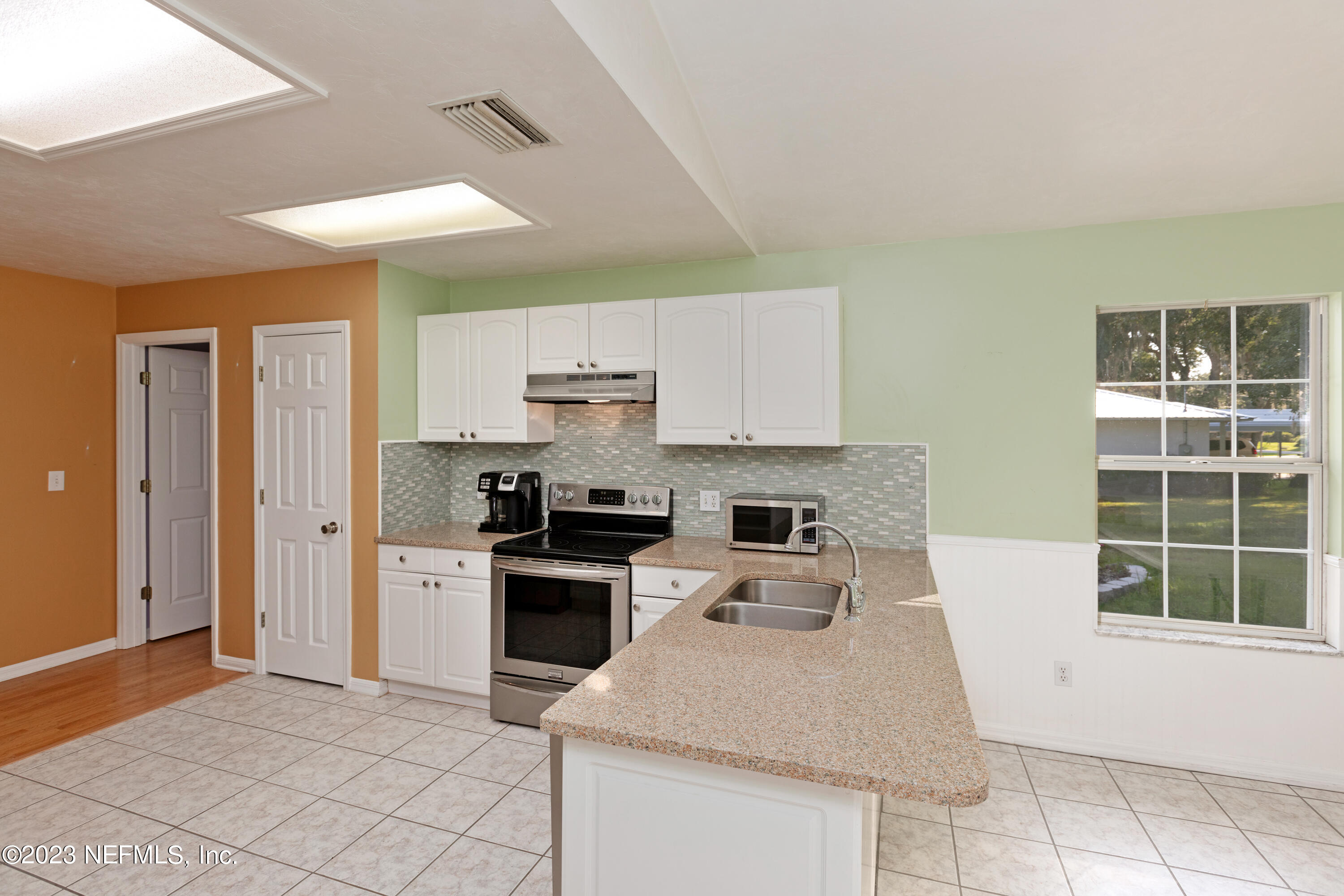 445 Southeast 28th Loop Melrose, FL 32666 - Photo 35 of 75 a kitchen with granite countertop a stove a sink a refrigerator and white cabinets with wooden floor
