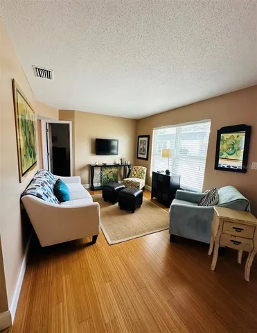 a living room with furniture hard wood floor and a flat screen tv