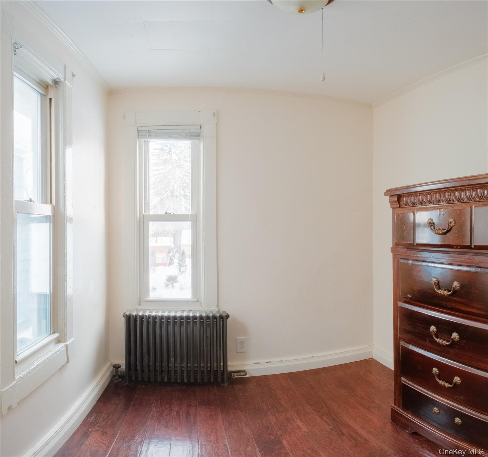 925 Constant Avenue Peekskill, NY 10566 - Photo 13 of 28 Empty room with radiator heating unit, dark wood-style flooring, and crown molding