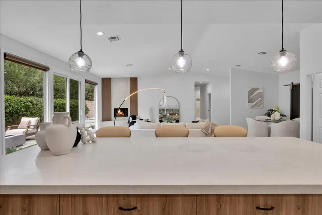 a kitchen with stainless steel appliances kitchen island granite countertop a table chairs and a refrigerator