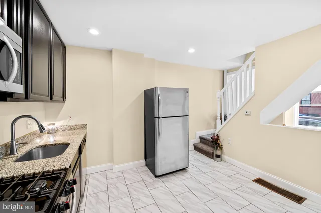 a kitchen with sink a refrigerator and a stove top oven