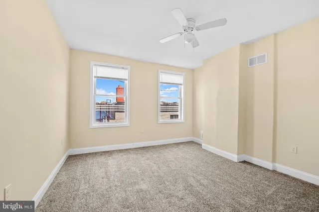 an empty room with windows and fan