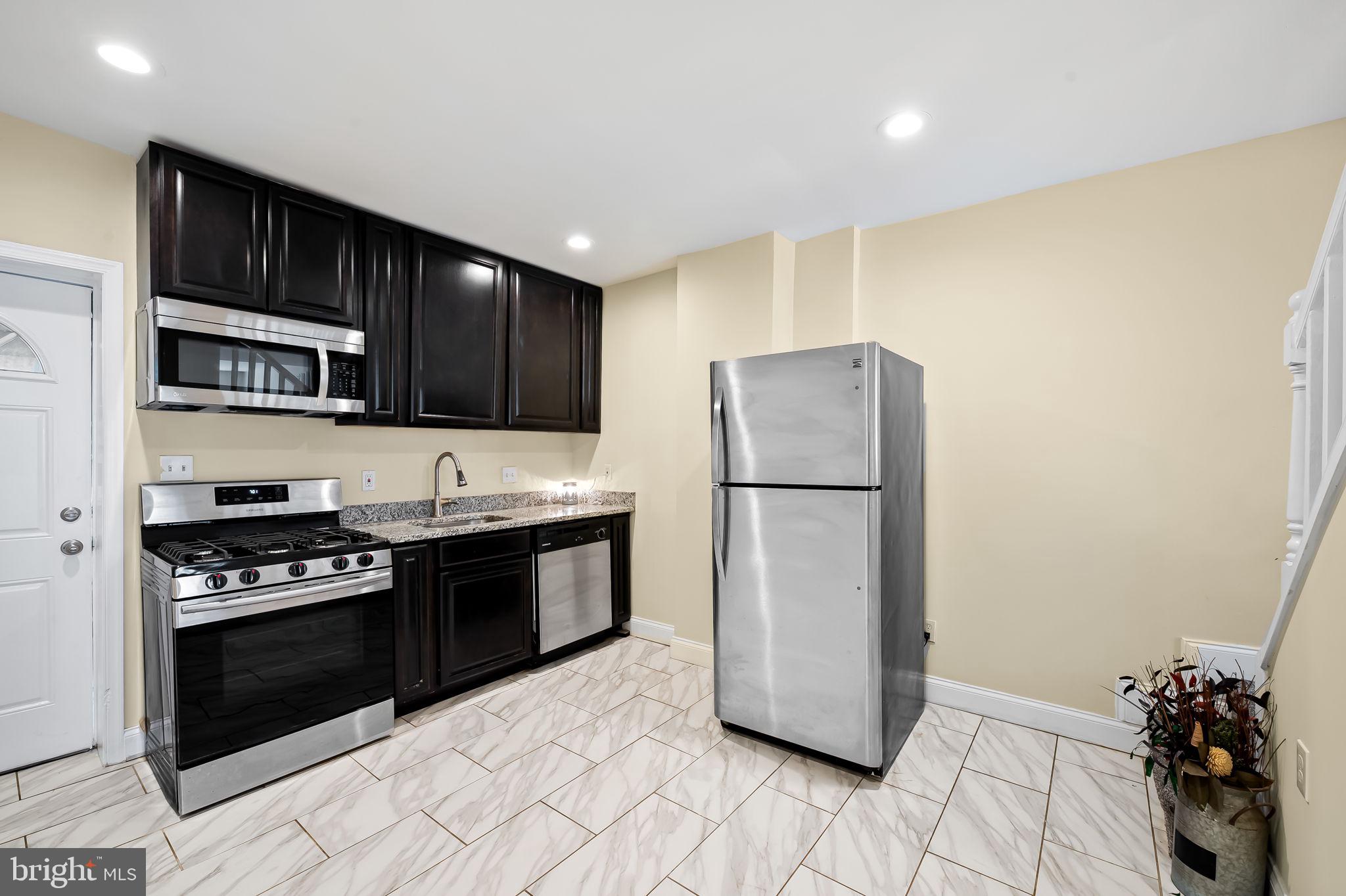 307 Fagley Street Baltimore, MD 21224 - Photo 8 of 24 a kitchen with a refrigerator a stove and wooden cabinets