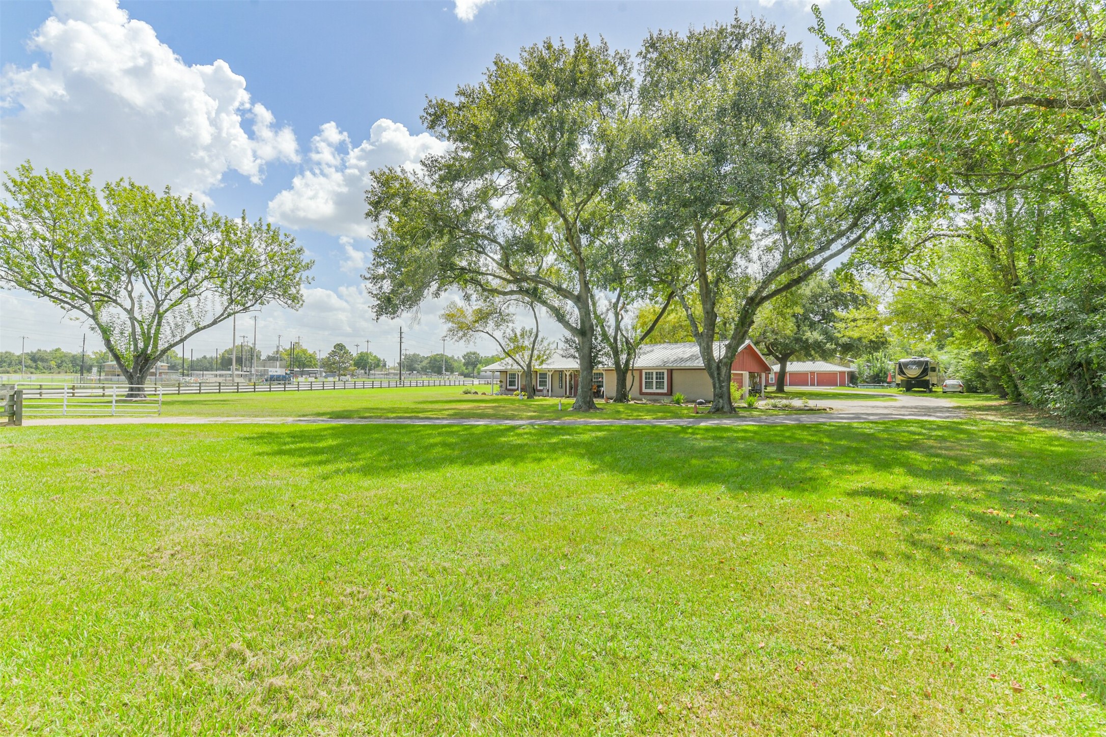 307 West Hufsmith Road Tomball, TX 77375 - Photo 35 of 44 Expansive green lawn with mature trees surrounds a charming ranch-style home, offering a serene and private retreat with ample outdoor space.