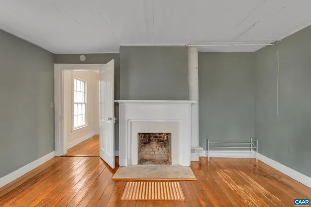 a view of a livingroom with wooden floor and a fireplace