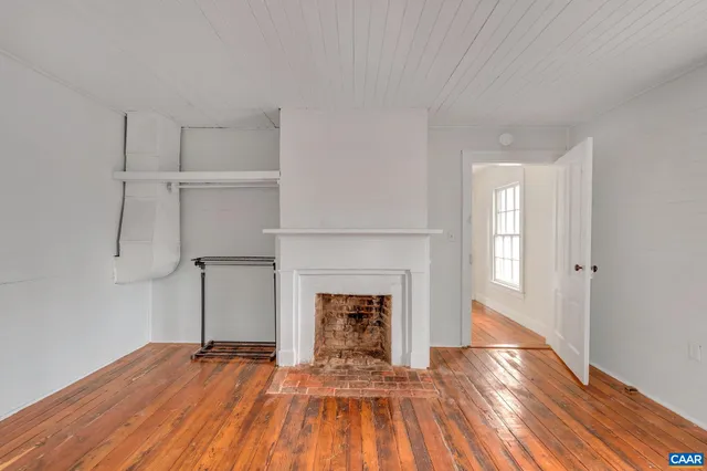 a view of empty room with wooden floor and fireplace