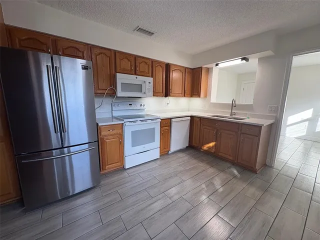 a kitchen with stainless steel appliances granite countertop a refrigerator a sink dishwasher a stove with wooden floors and cabinets