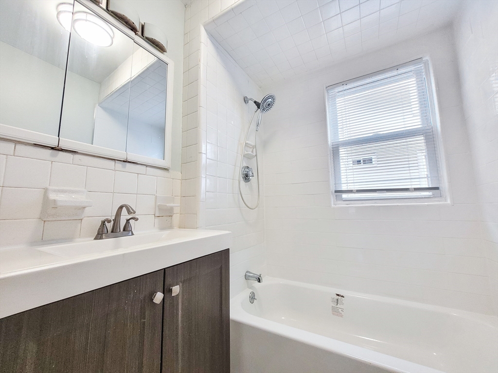 37-39 Juniper Street, Unit 39 1 Boston, MA 02119 - Photo 10 of 12 a bathroom with a tub a sink and mirror